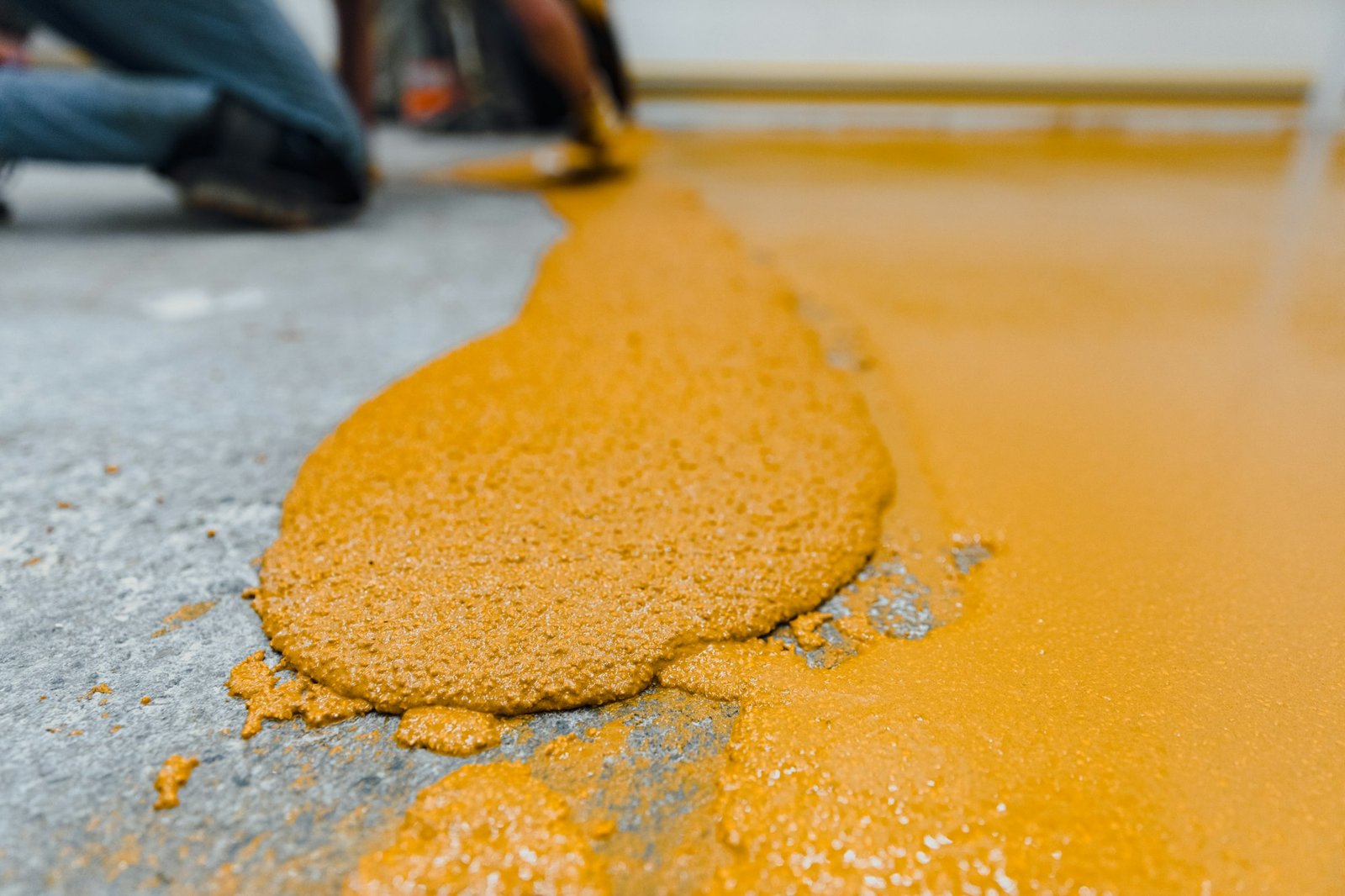 Professional construction worker applying floor paint or a new layer for a epoxy cast coating floor