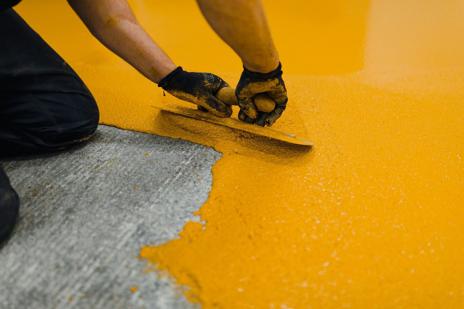 Professional construction worker applying floor paint or a new layer for a epoxy cast coating floor